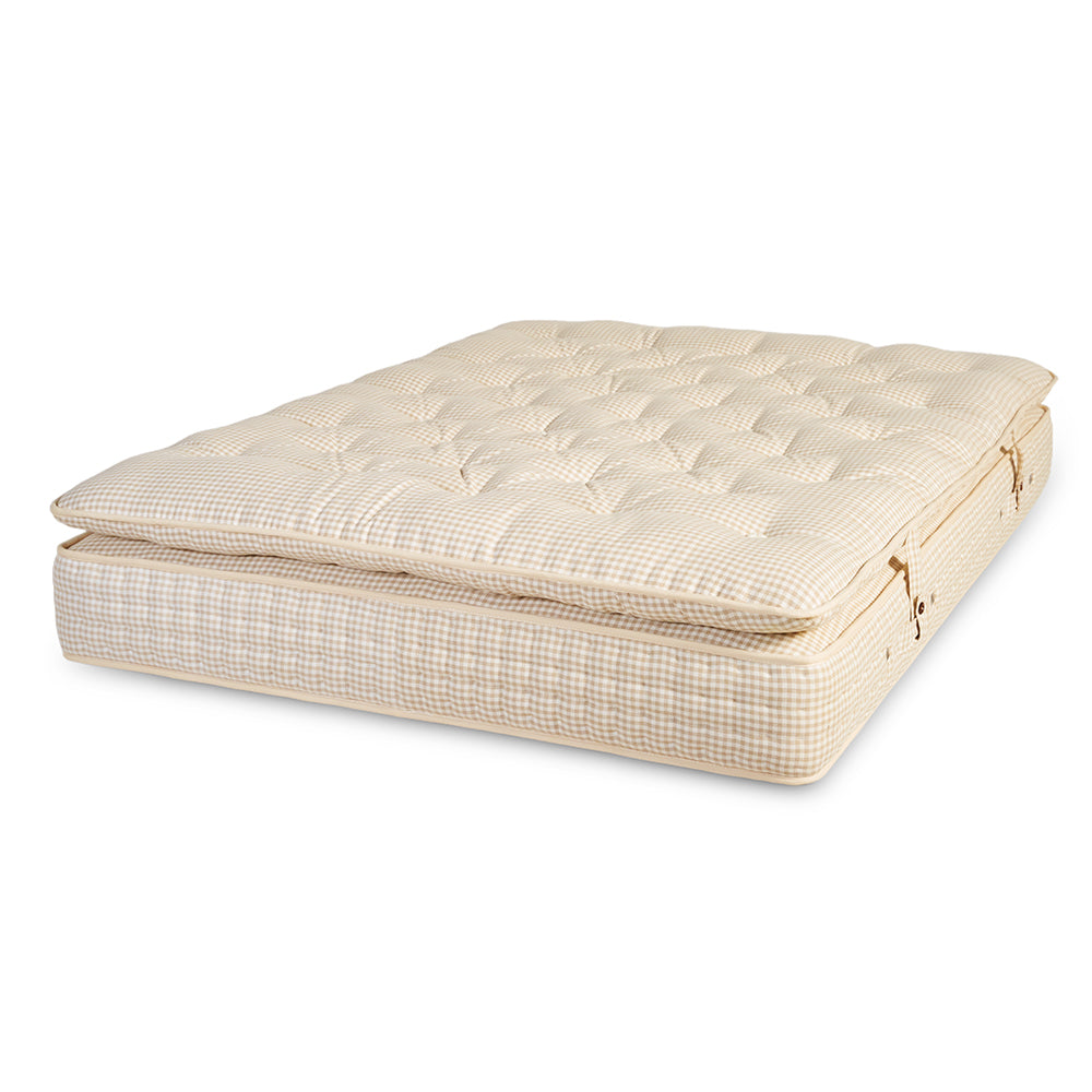 A folded mattress topper or mattress cover in a light beige color, featuring a quilted check pattern on top and a fine checkered grid pattern on the sides, shown on a plain white background.