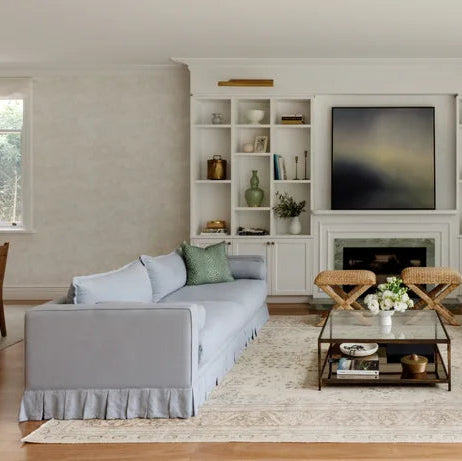 Modern living room with blue crafted Sofia 3 seat sofa, white armchair, and a television on a wall.